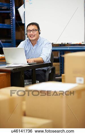Worker In Warehouse Wearing Headset And Using Laptop View Large Photo Image Stock Photograph - Worker In Warehouse Wearing Headset And Using Laptop. Fotosearch