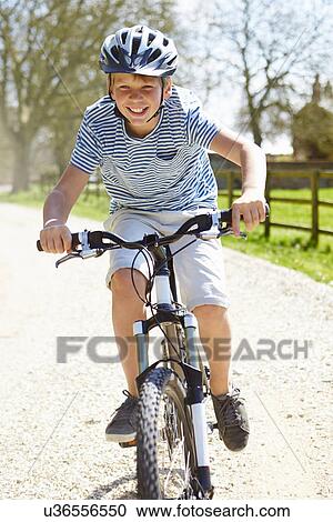 Stock Image - Young Boy Riding Bike Along Country Track. Fotosearch