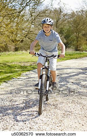Stock Image - Young Boy Riding Bike Along Country Track. Fotosearch