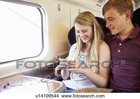 Picture - Young Couple Listening To Music On Train Journey. Fotosearch