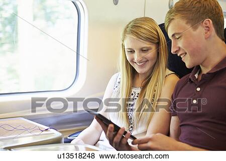 Stock Photo - Young Couple Reading E Book On Train Journey. Fotosearch