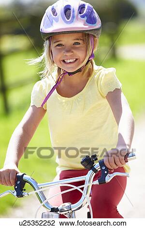 Stock Image - Young Girl Riding Bike Along Country Track. Fotosearch