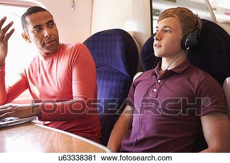 Stock Image - Young Man Disturbing Train Passengers With Loud Music. Fotosearch
