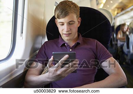 Stock Photo - Young Man Reading E Book On Train Journey. Fotosearch