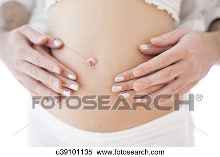 Stock Photography - Couple holding pregnant woman's abdomen. Fotosearch