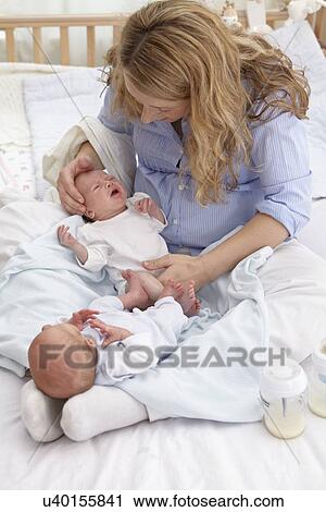Stock Image - Mother and two week old twins. Fotosearch