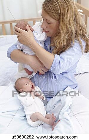 Stock Image - Mother and two week old twins. Fotosearch