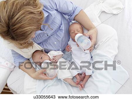 Stock Image - Mother feeding two week old twins. Fotosearch