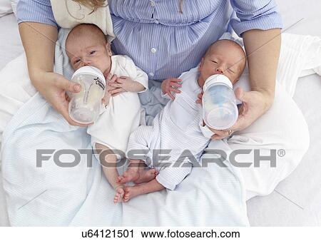Stock Image - Mother feeding two week old twins. Fotosearch