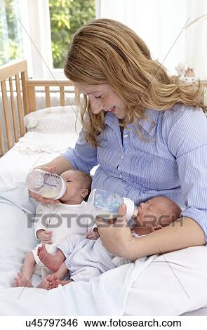 Stock Photograph - Mother feeding two week old twins. Fotosearch