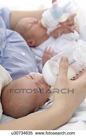 Stock Photography - Mother feeding two week old twins. Fotosearch