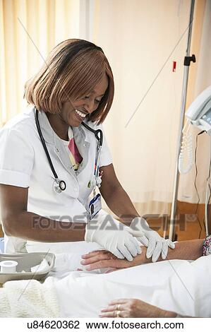 Stock Image - Nurse preparing a patient for an IV line. Fotosearch
