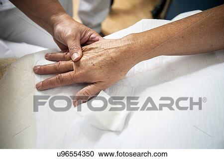 Stock Image - Nurse preparing a patient for an IV line. Fotosearch