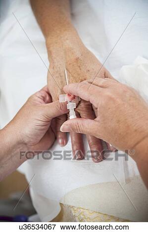Nurse preparing a patient for an IV line View Large Photo Image Stock Photo - Nurse preparing a patient for an IV line. Fotosearch