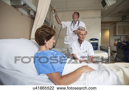Stock Image - Nurses preparing a patient for an IV line. Fotosearch