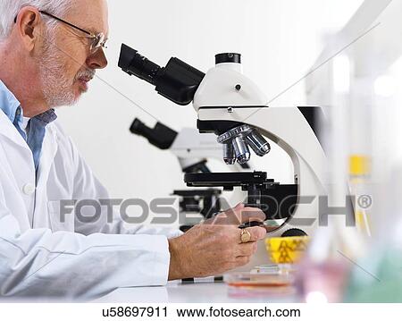 Stock Image - Scientist using a light microscope. Fotosearch