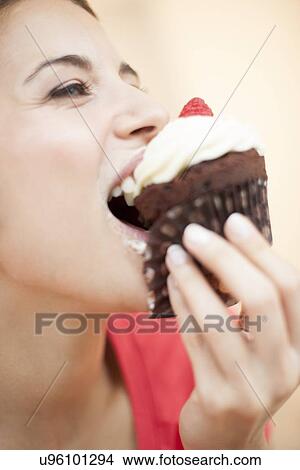 Woman eating a cup cake View Large Photo Image Picture - Woman eating a cup cake. Fotosearch