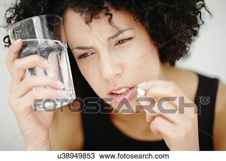 Stock Image - Woman taking a pill. Fotosearch