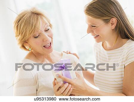 Adult daughter giving present to mother View Large Photo Image Stock Image - Adult daughter giving present to mother. Fotosearch