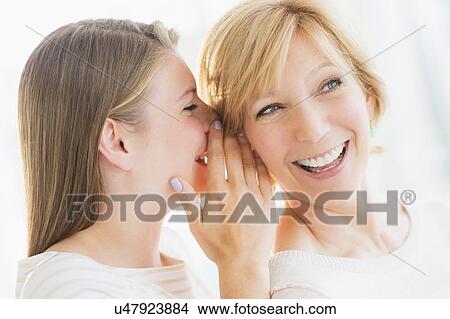 Picture - Adult daughter whispering into mother's ear. Fotosearch