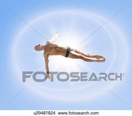 Athletic swimmer mid-air against blue sky View Large Photo Image Picture - Athletic swimmer mid-air against blue sky. Fotosearch