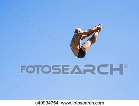 Athletic swimmer mid-air against blue sky View Large Photo Image Picture - Athletic swimmer mid-air against blue sky. Fotosearch