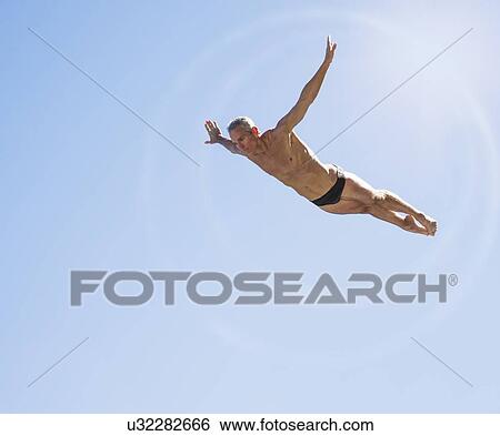 Athletic swimmer mid-air against blue sky View Large Photo Image Stock Photograph - Athletic swimmer mid-air against blue sky. Fotosearch