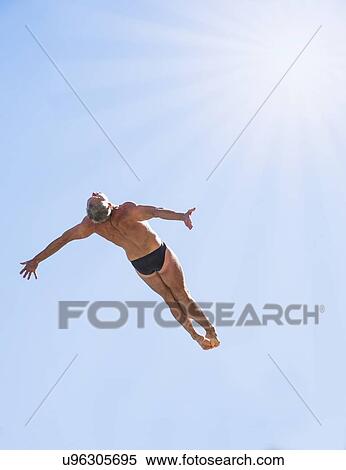 Stock Photography - Athletic swimmer mid-air against blue sky. Fotosearch