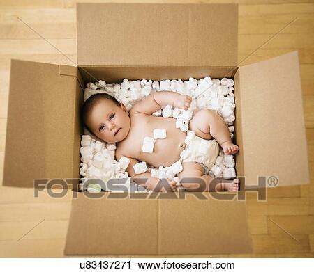 Stock Image - Baby girl (2-5 months) in cardboard box. Fotosearch