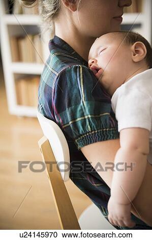 Stock Image - Baby girl (2-5 months) sleeping in mother's arms. Fotosearch