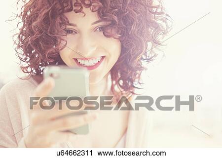 Stock Image - Beautiful brunette woman text messaging. Fotosearch