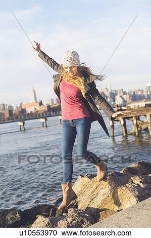 Blond woman stepping on stones by river, skyline in background View Large Photo Image Stock Image - Blond woman stepping on stones by river, skyline in background. Fotosearch