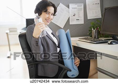Picture - Business woman holding water bottle and yoga mat. Fotosearch