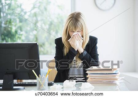 Businesswoman blowing nose in office View Large Photo Image Picture - Businesswoman blowing nose in office. Fotosearch