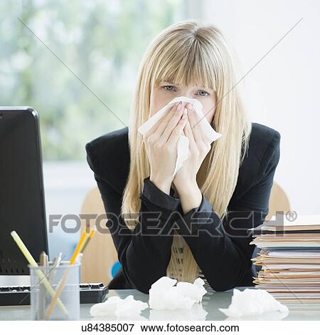 Businesswoman blowing nose in office View Large Photo Image Stock Photo - Businesswoman blowing nose in office. Fotosearch