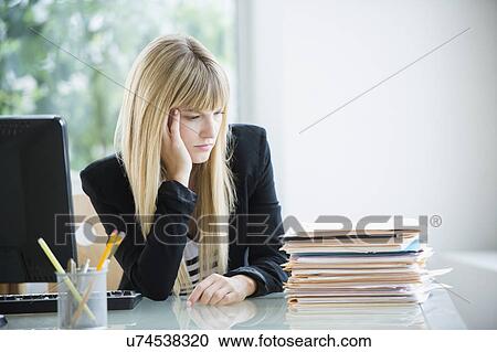 Stock Image - Businesswoman looking at stack of files. Fotosearch