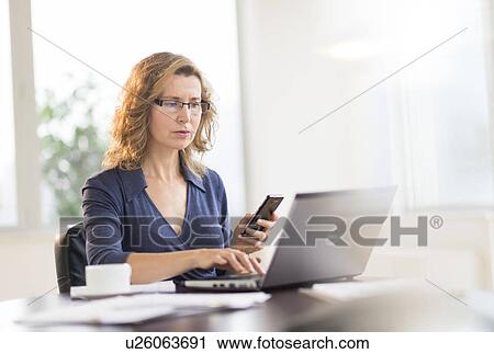 Businesswoman using laptop and phone View Large Photo Image Stock Image - Businesswoman using laptop and phone. Fotosearch
