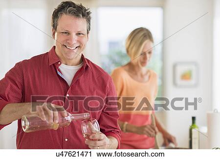 Stock Image - Couple cooking at home, focus on man. Fotosearch