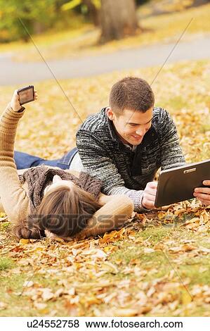 Couple in Central Park using digital tablet and cell phone View Large Photo Image Stock Photo - Couple in Central Park using digital tablet and cell phone. Fotosearch