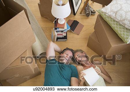Stock Image - Couple lying on floor of new home. Fotosearch