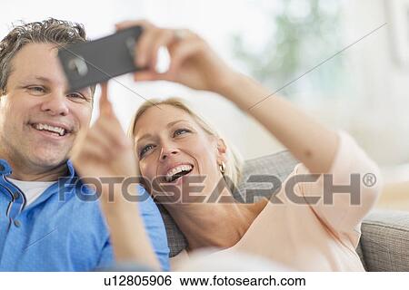 Stock Photograph - Couple taking self-portrait photo with smartphone. Fotosearch