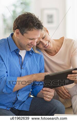 Couple using tablet pc at home View Large Photo Image Stock Photo - Couple using tablet pc at home. Fotosearch