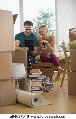 Stock Photograph - Couple using tablet pc in new home. Fotosearch