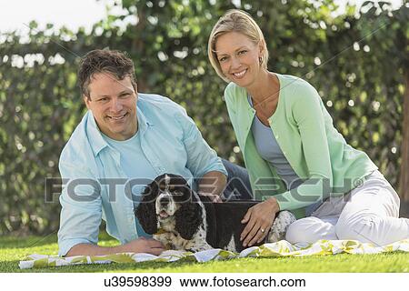 Stock Photo - Couple with dog relaxing on grass. Fotosearch