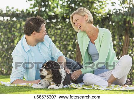 Stock Photo - Couple with dog relaxing on grass. Fotosearch
