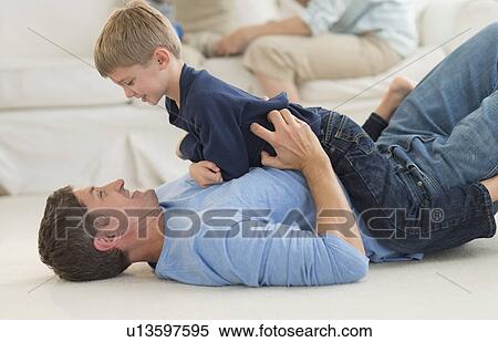 Stock Photography - Father with son (6-7) playing at home. Fotosearch