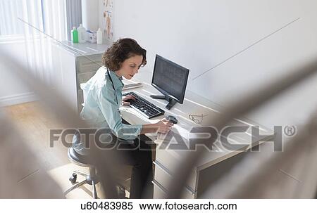 Stock Photography - Female doctor working on computer. Fotosearch