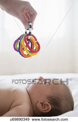 Hand holding colorful toy above baby girl (2-5 months) View Large Photo Image Stock Photo - Hand holding colorful toy above baby girl (2-5 months). Fotosearch