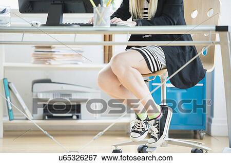Stock Photo - Legs of female designer sitting at desk. Fotosearch