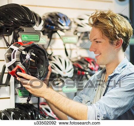 Man choosing helmet in bike shop View Large Photo Image Stock Image - Man choosing helmet in bike shop. Fotosearch